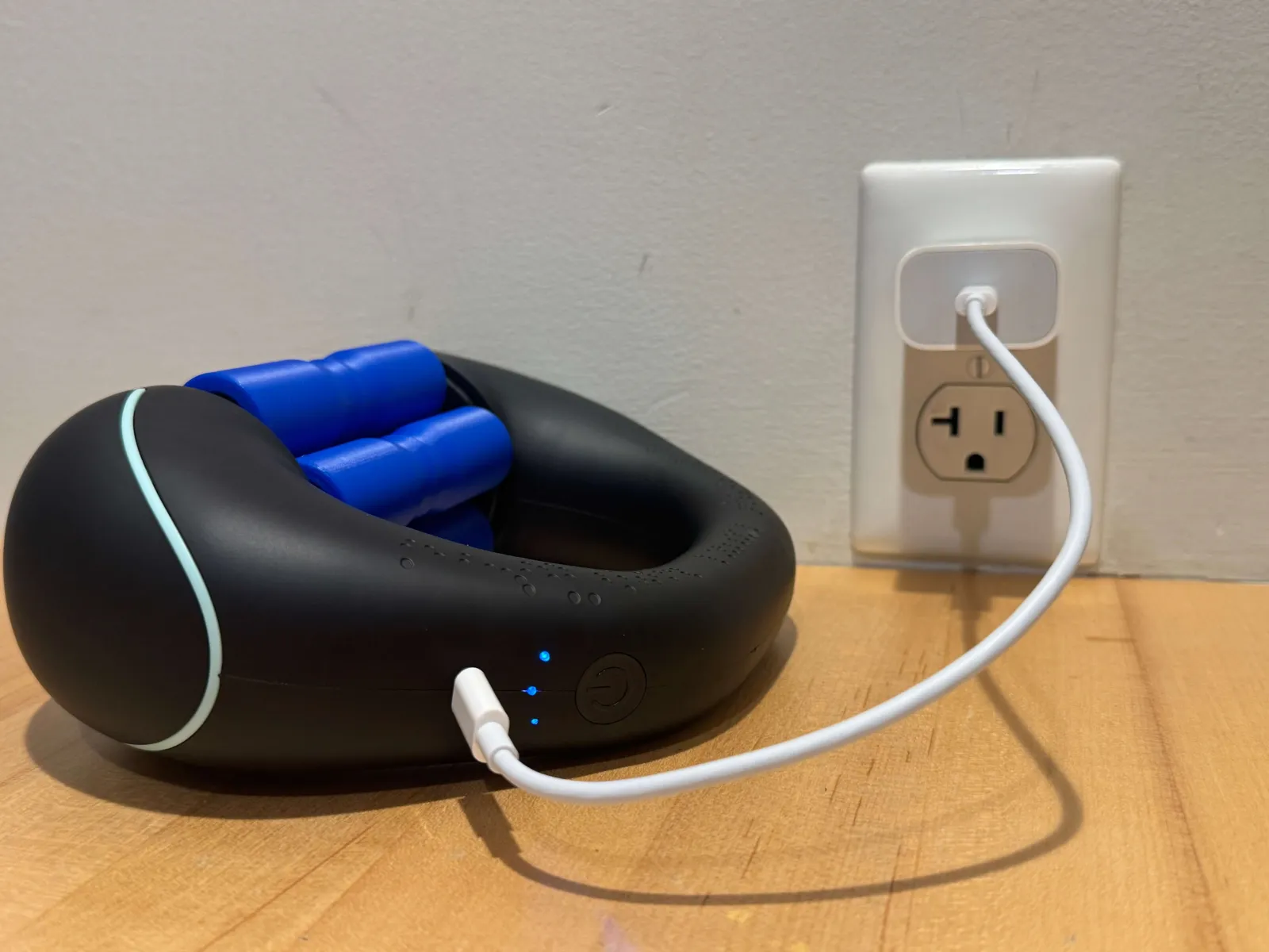 The VascuVive Pulse charging over USB-C on a wooden desk